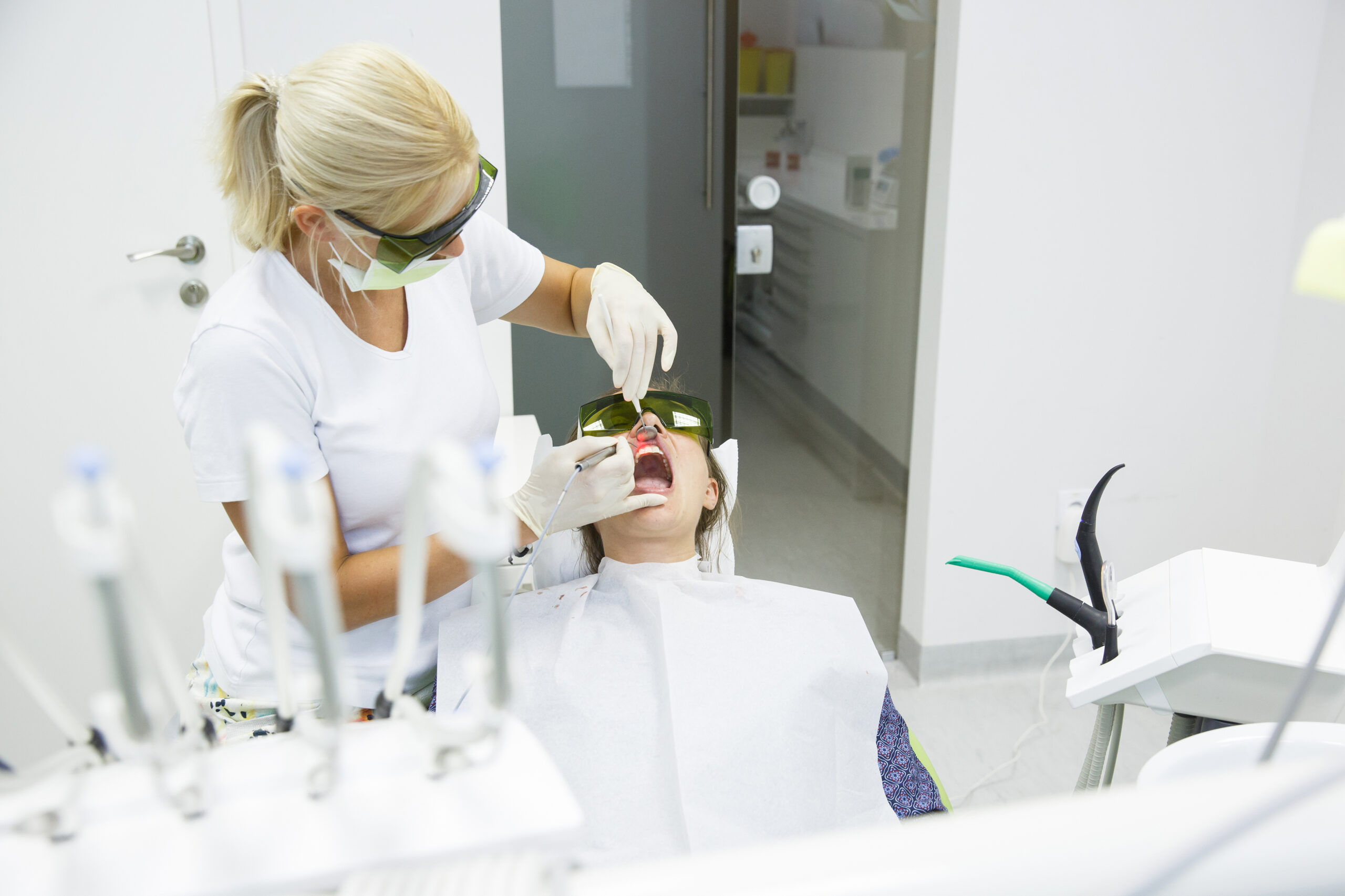 Female patient and dental assistant wearing protective goggles as the patient gets periodontic laser therapy.